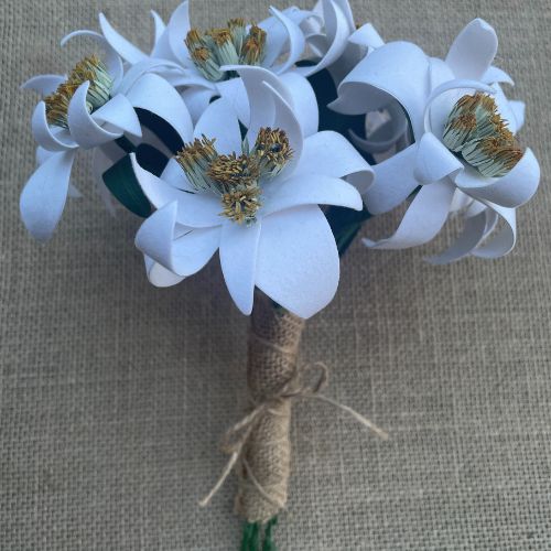 Bouquet da sposa artigianale con stelle alpine stilizzate in carta, stami dorati e gambo rivestito in juta naturale per un matrimonio eco-chic o moderno.