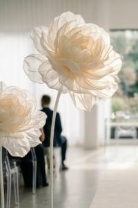 Peonie giganti in organza color avorio su steli alti utilizzate come scenografia floreale per un allestimento di matrimonio elegante.